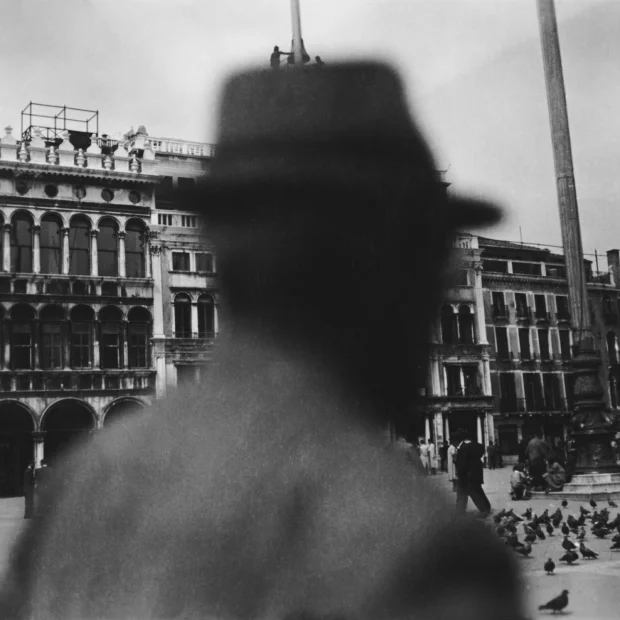 Hombre con sombrero, de pie delante de un edificio.